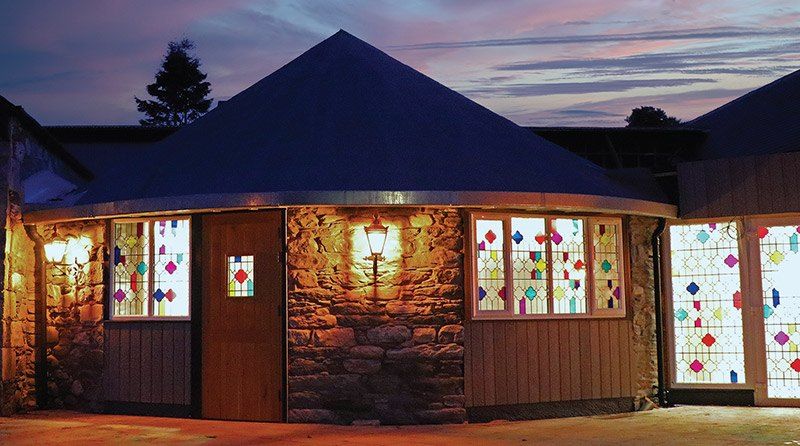 The circular stone-and-timber exterior of The Roundhouse Inn lit up at dusk in Bridge of Tilt, Blair Atholl