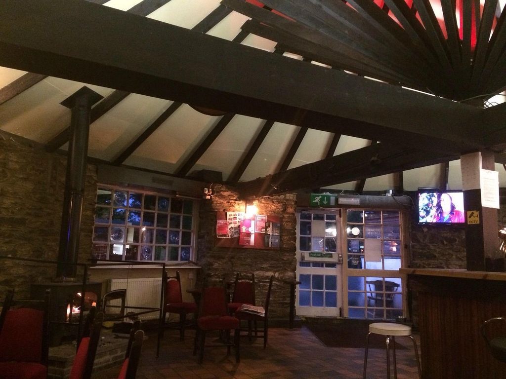 The lounge seating area with a lit fire and coloured stained-glass window at The Roundhouse Inn
