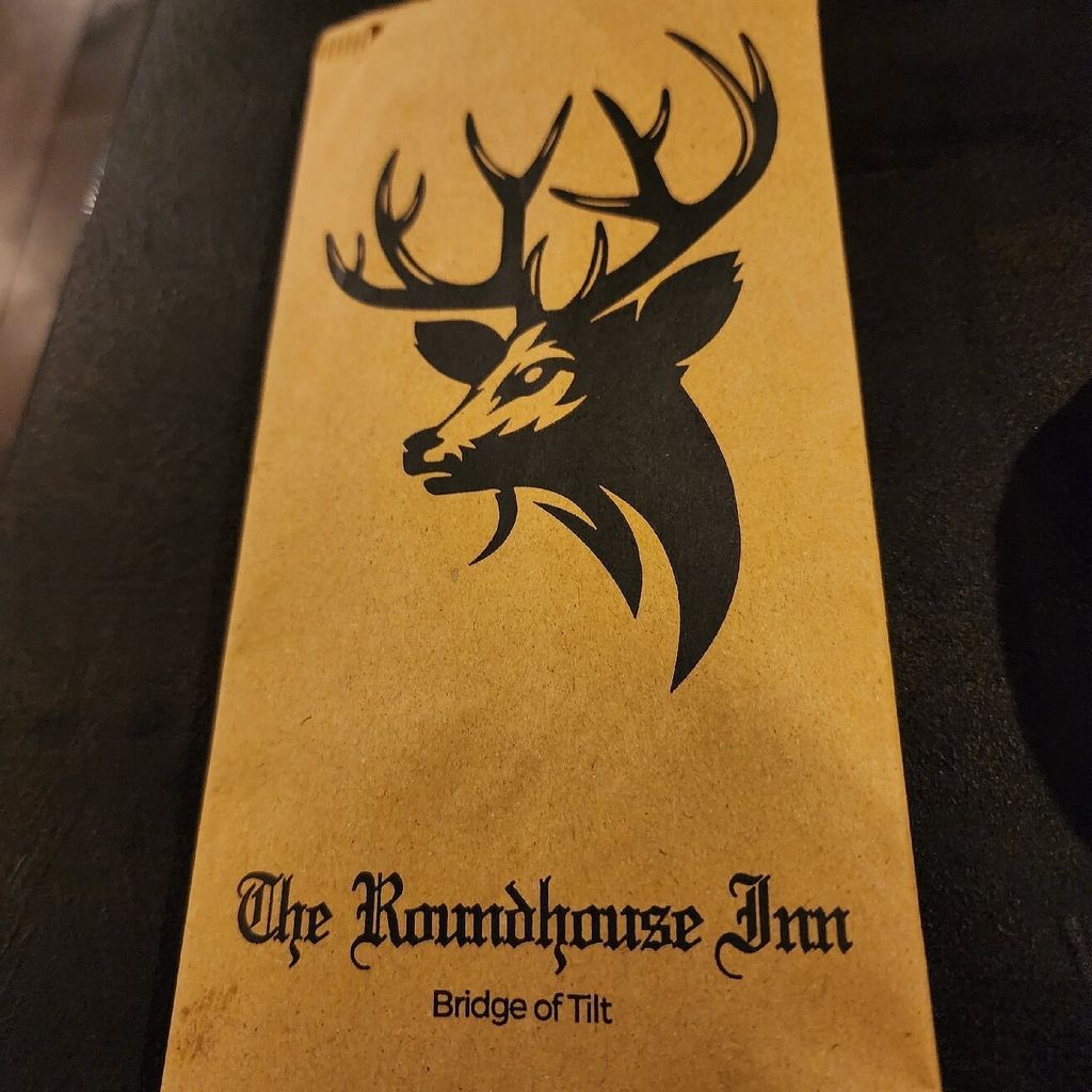 The Roundhouse Inn menu with its Highland stag logo resting on a wooden pub table